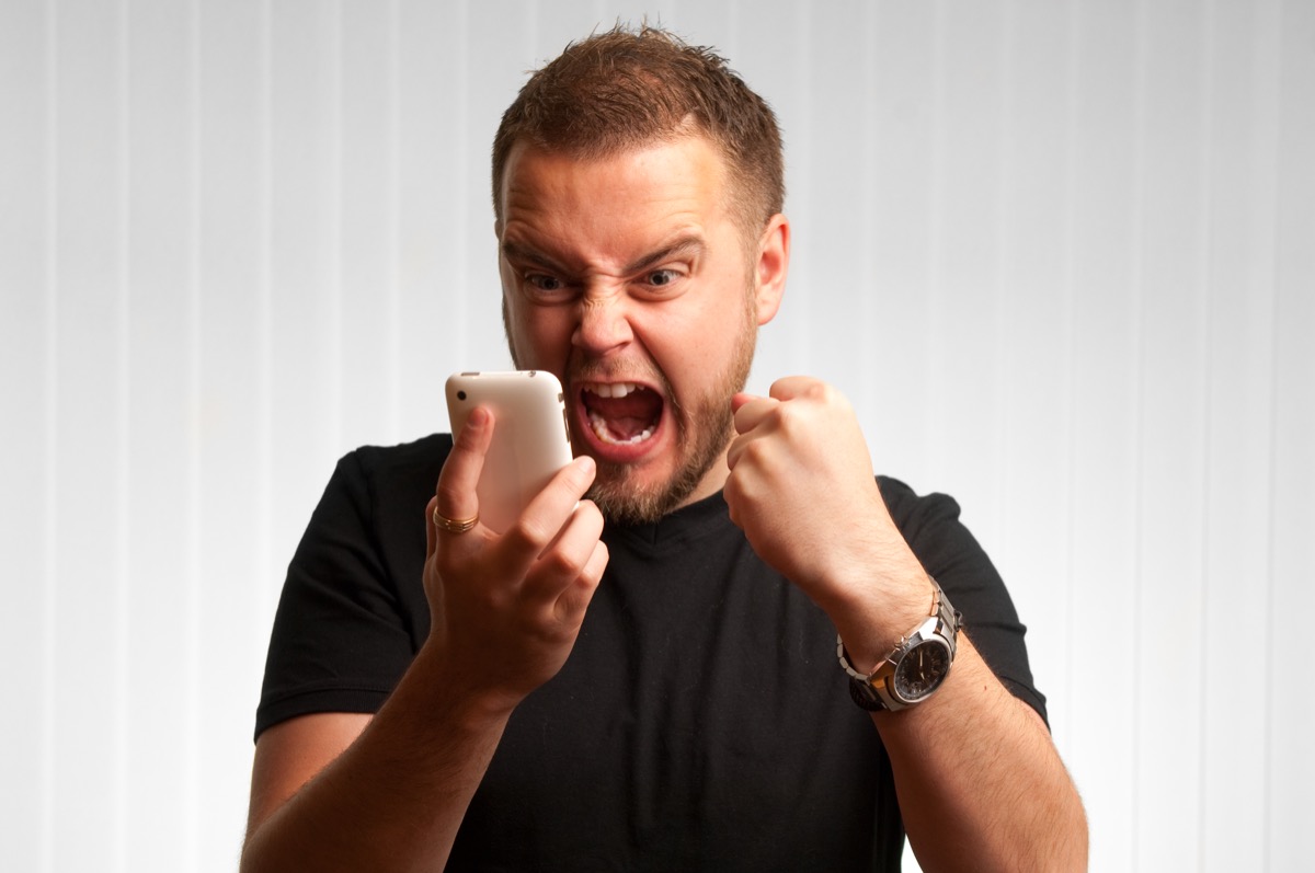 Angry man screaming into the phone and cursing during a bad conversation