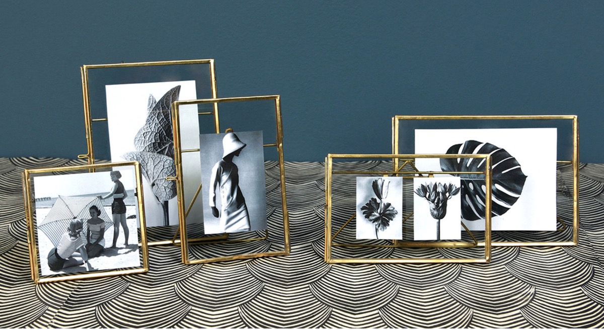 five pictures in brass frames on patterned table with blue background