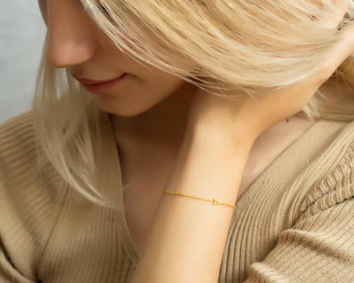 white woman wearing gold letter bracelet