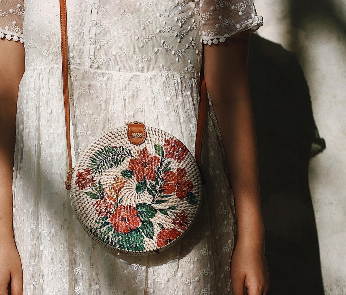 woman wearing floral rattan bag and white dress