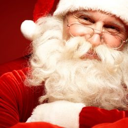 closeup of santa clause with white beard, small glasses, in red and white suit