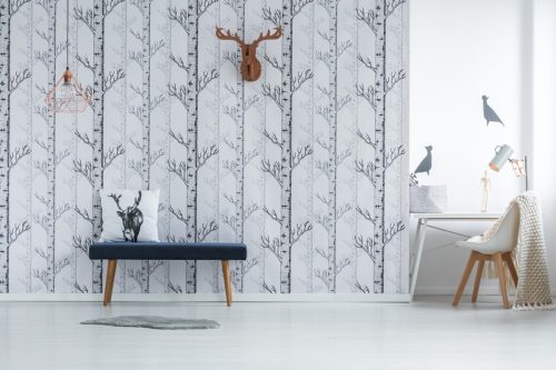 modern bedroom with white tree wallpaper and faux deer head and black upholstered bench