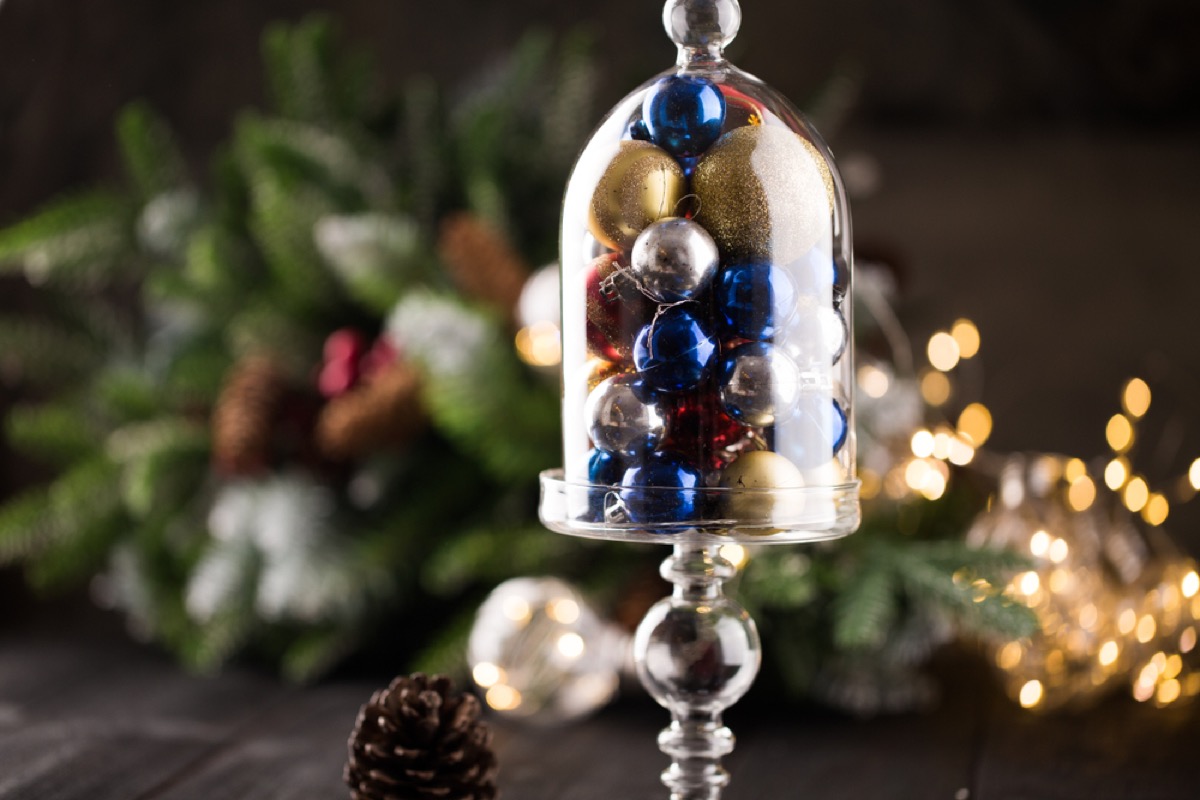 clear glass cloche full of blue and gold christmas ornaments