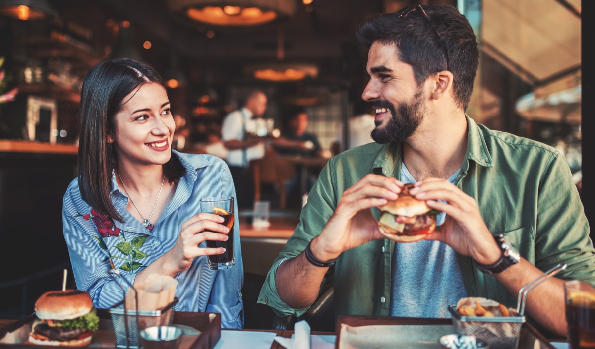 Couple eating burgers at a restaurant for dinner