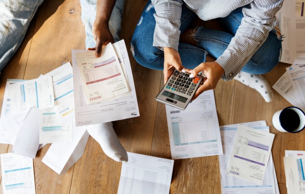 couple sitting on floor surrounded by bills and invoices