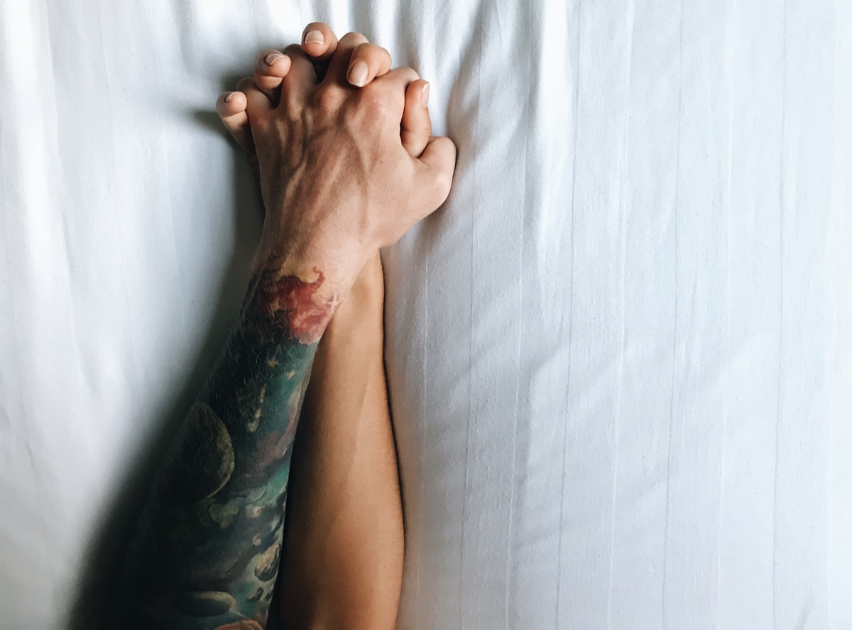 couple's hands in bed