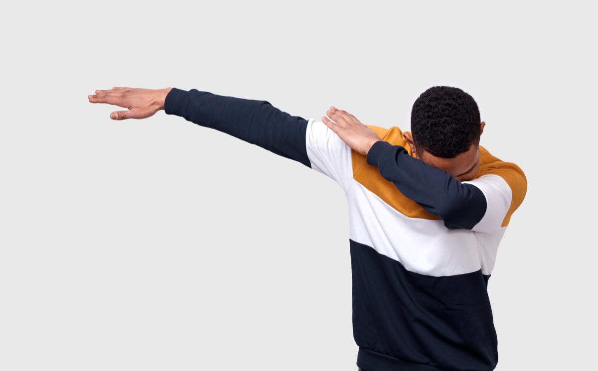 a man dabbing in front of a white wall