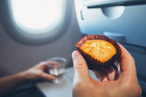 Person eating a muffin on an airplane