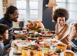 Happy black family talking during Thanksgiving meal at dining table.