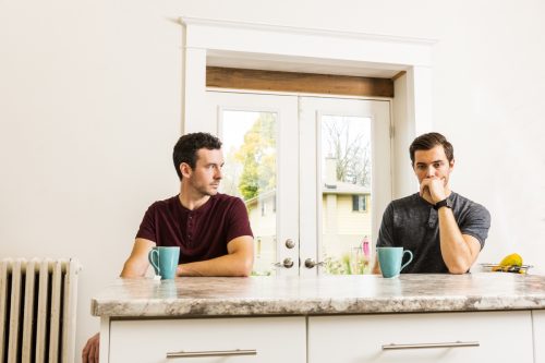 gay couple experiencing relationship issues at home while sitting at kitchen island