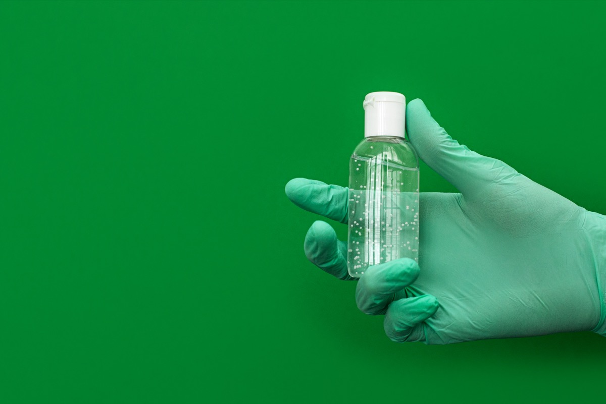 Hand in latex green medical protection gloves white sanitizer. Coronavirus optimistic hygiene concept. Copy space