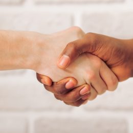White person and black person shaking hands