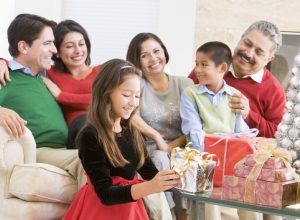 hispanic family with four adults and two children opening gifts in holiday attire