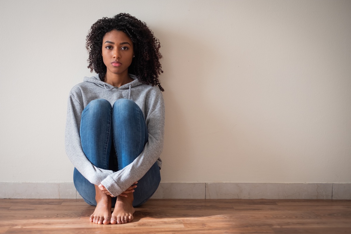 young black woman clutching her knees and looking concerned