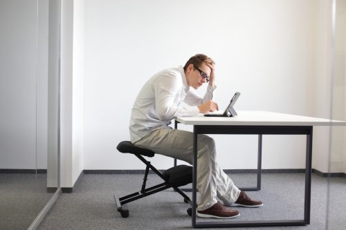 white man with bad posture slouching over his computer