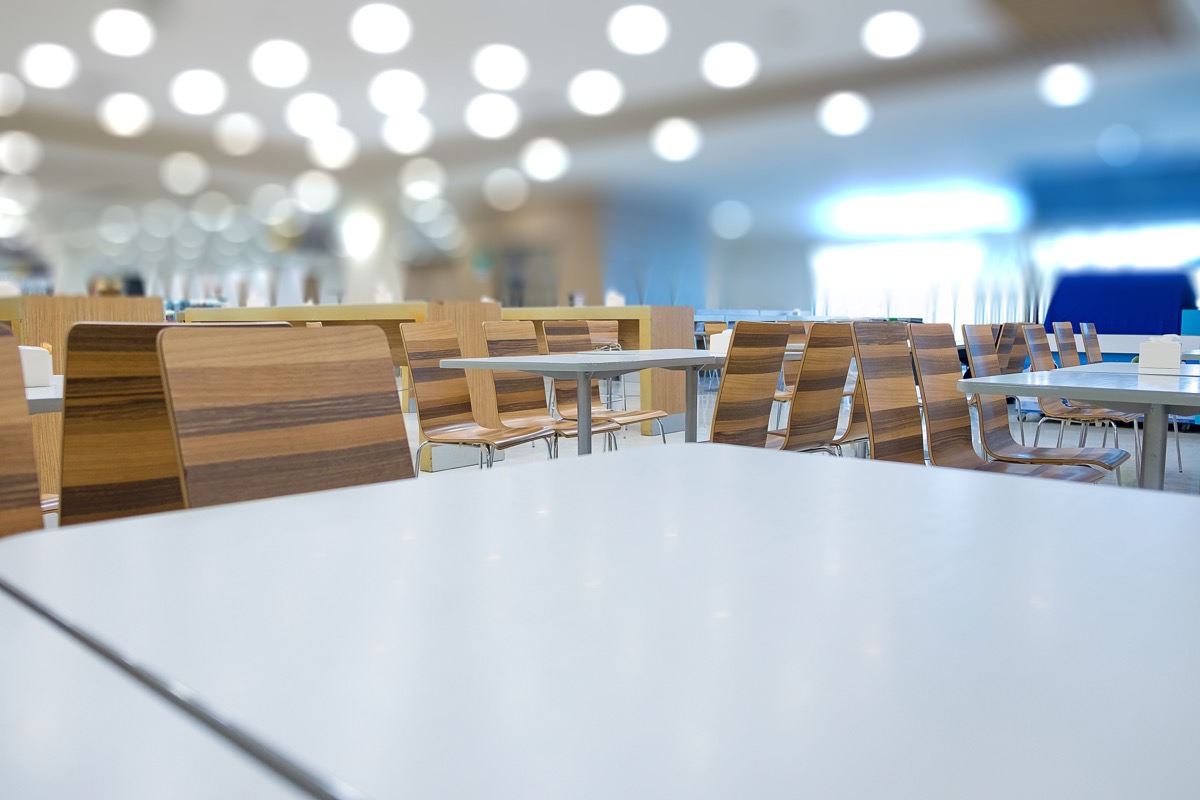 Interior of white table and wooden table on food court in shopping mall