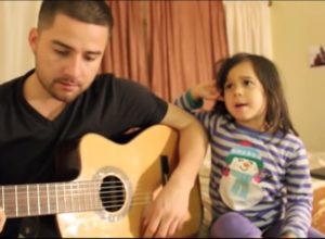 young man playing acoustic guitar next to young girl