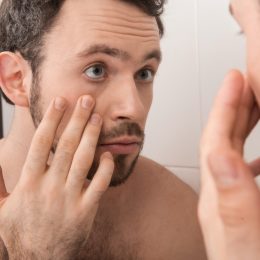 young man looking at his eye in the mirror