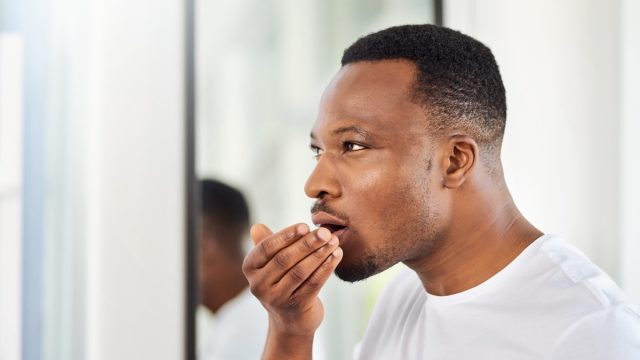 Black man smelling his breath
