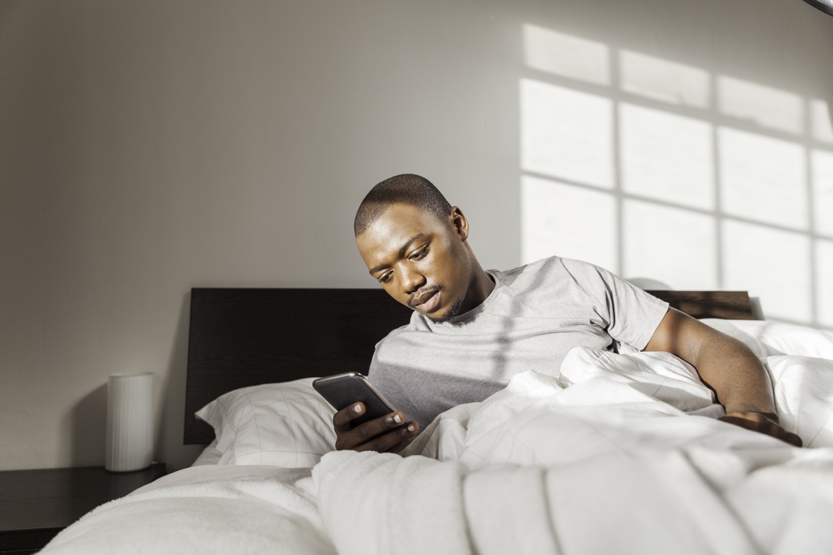 man using his phone in his bed