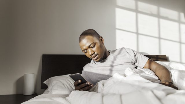 man using his phone in his bed