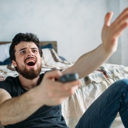Man is angry while he is watching television on the floor