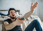 Man is angry while he is watching television on the floor