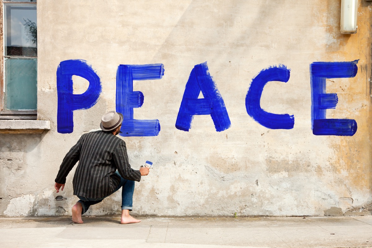 man writing peace on wall