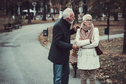 Elderly Couple in Warm Clothing Arguing in a Park During Cold Autumn Day.