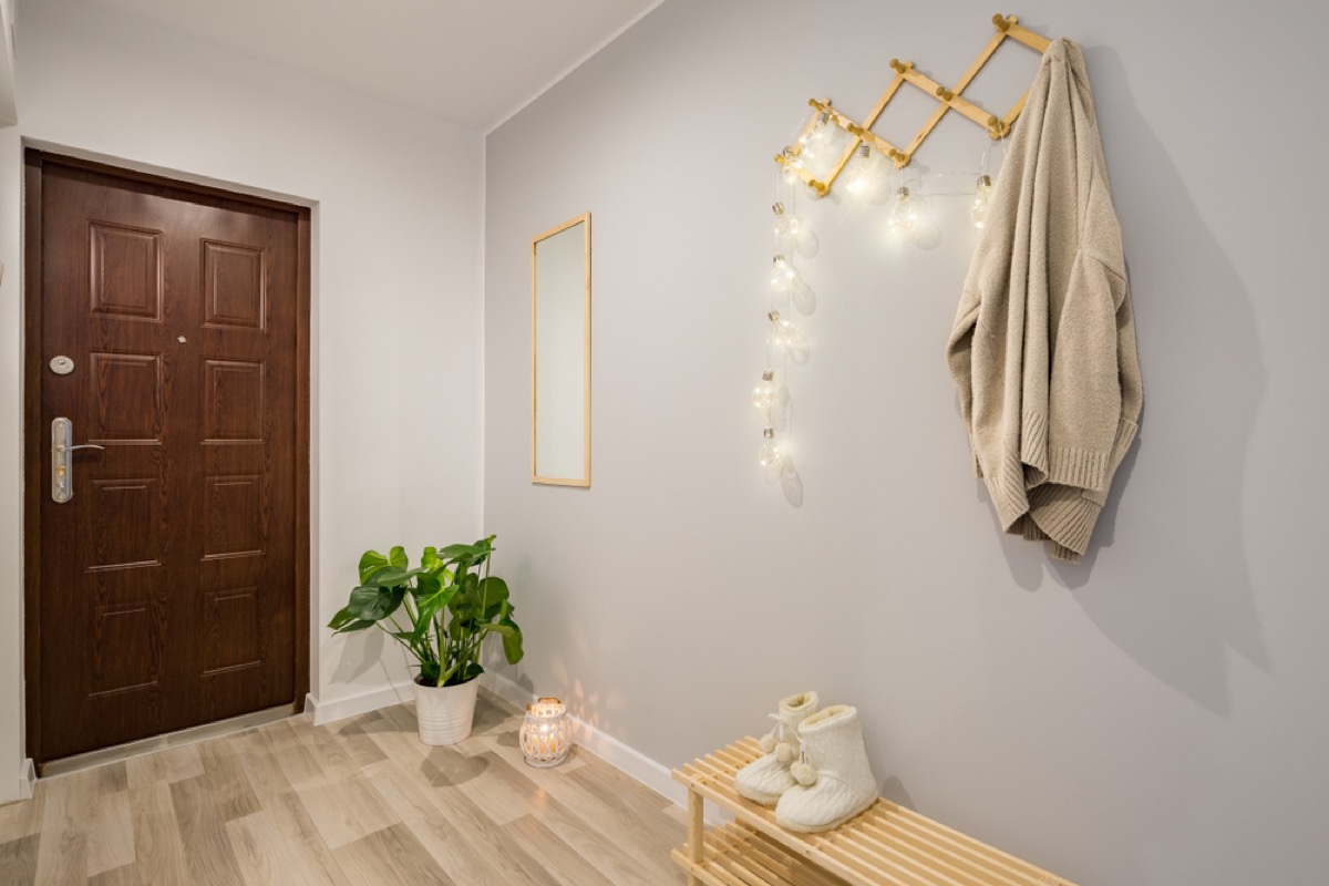gray mudroom with twinkly lights and white boots on a wooden bench