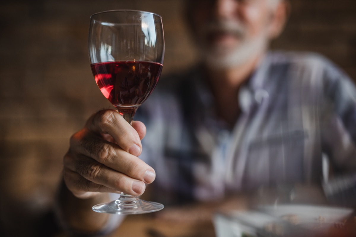 older man holding a wine glass of red wine