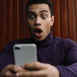 man of color looks shocked at phone
