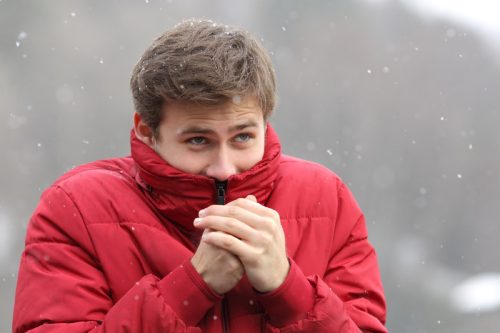 Omul alb în zăpadă cu jacheta trasă peste față