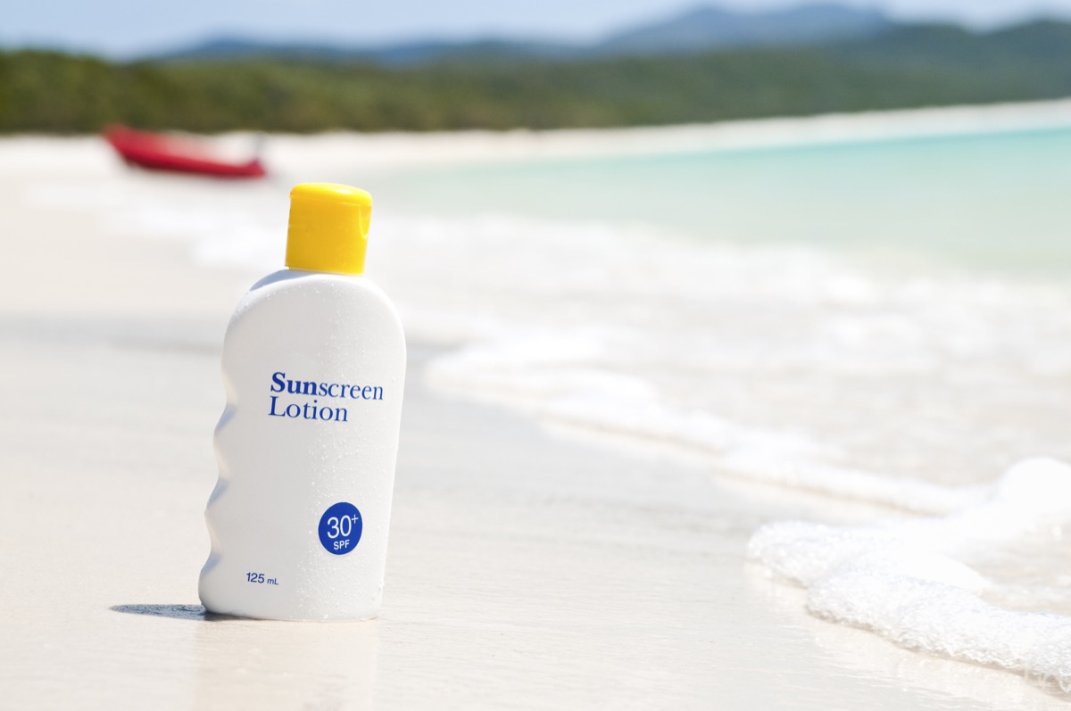 A bottle of sun protection cream on an idyllic beach.