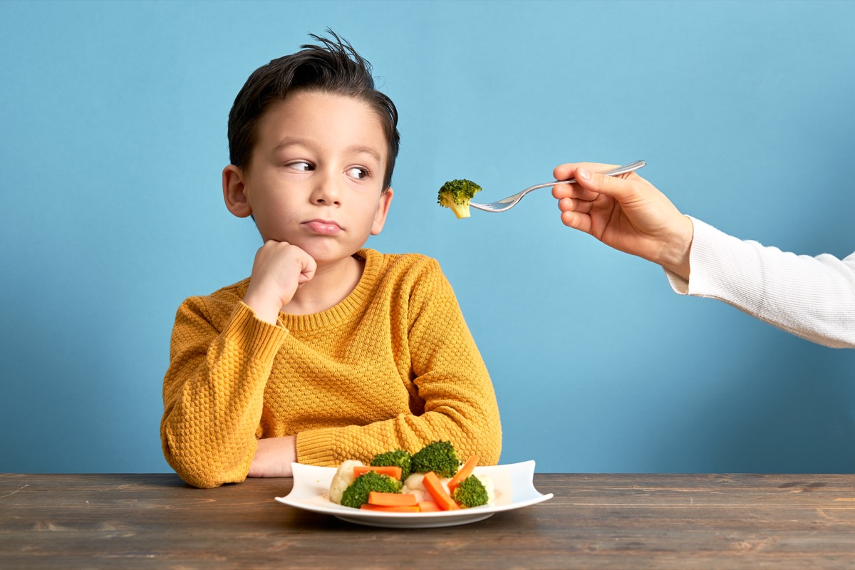 unhappy child eating broccoli