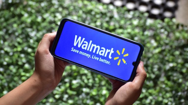 two hands holding a phone with the walmart app up on it