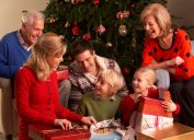 white grandparents, mother, father, and young daughter opening gifts