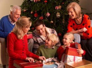 white grandparents, mother, father, and young daughter opening gifts