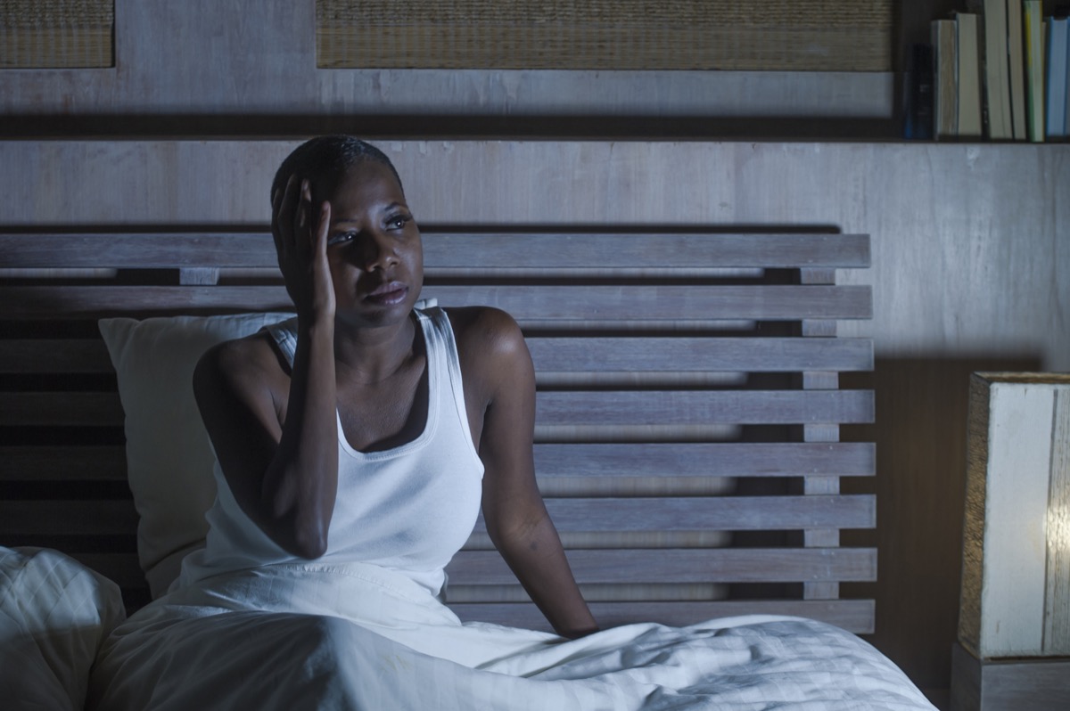 Black woman sitting awake in bed at night