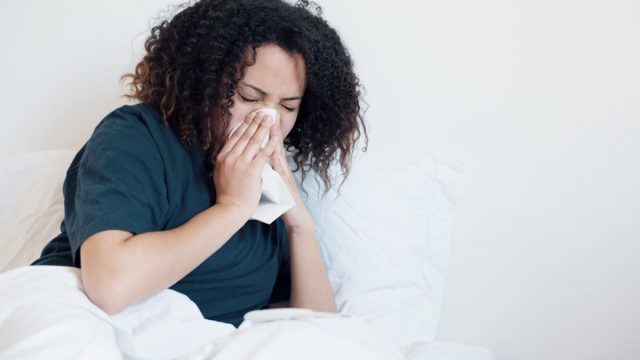 Woman sick and coughing in bed