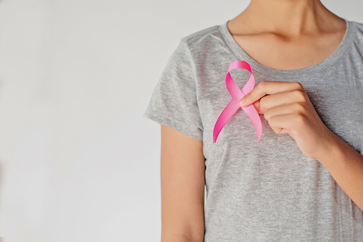 woman holding pink ribbon for breast cancer