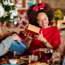 young black woman opening gifts sitting next to blonde friend holding box