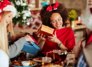 young black woman opening gifts sitting next to blonde friend holding box