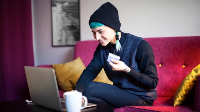 Young woman with blue hair shopping online in her living room