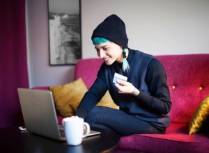 Young woman with blue hair shopping online in her living room