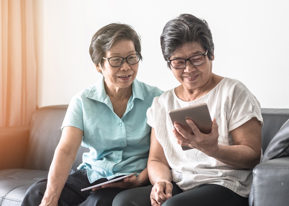 Asian elderly senior adult women (twin sisters) using mobile tablet