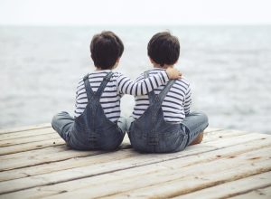 Twin brothers sitting on dock