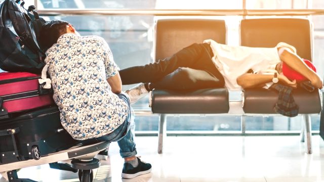 two travelers sleep in an airport