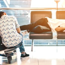 two travelers sleep in an airport