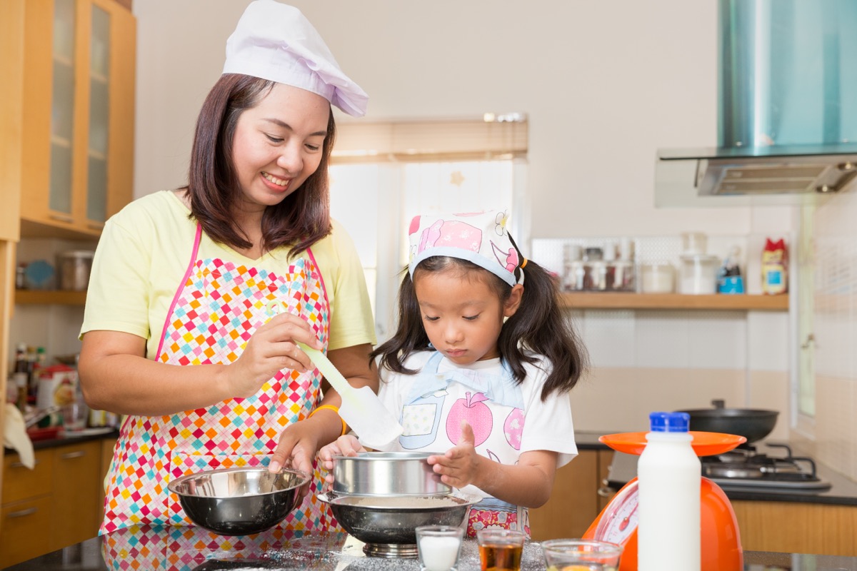 asian mom and young daughter making pancakes
